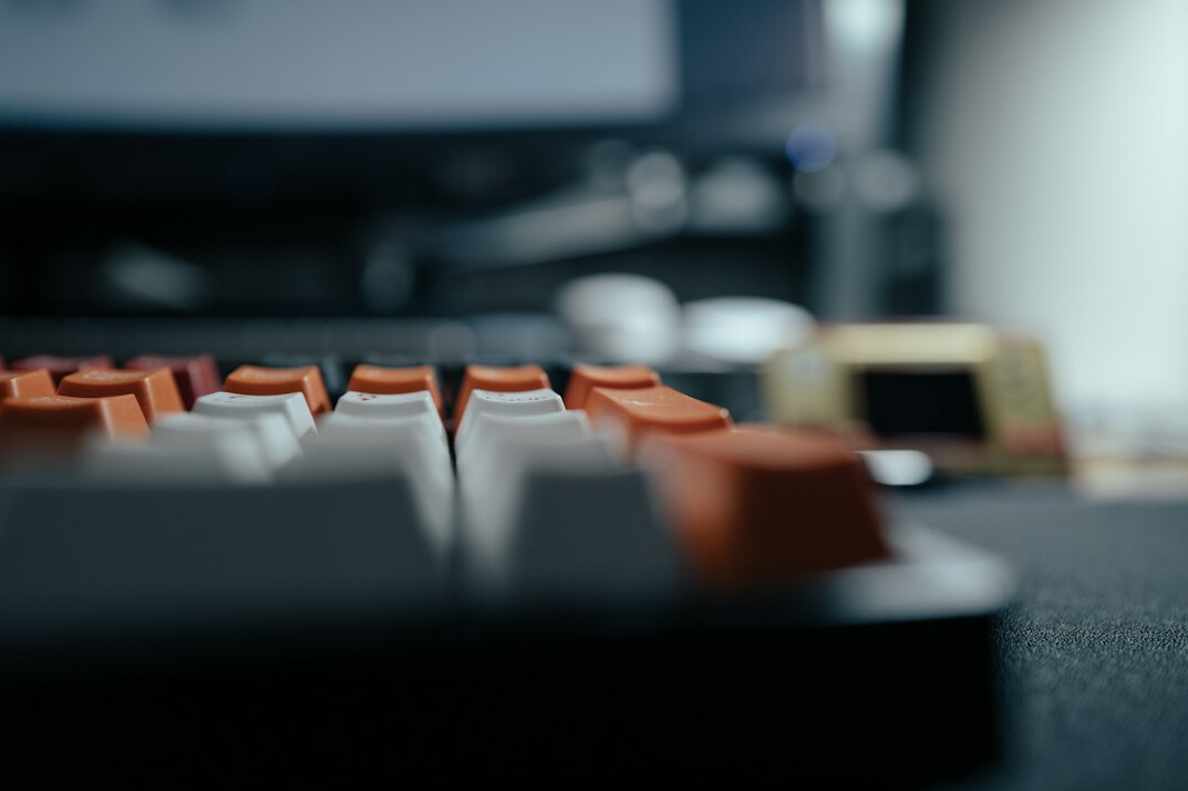 Close-up of a mechanical keyboard with a blurred code editor in the background